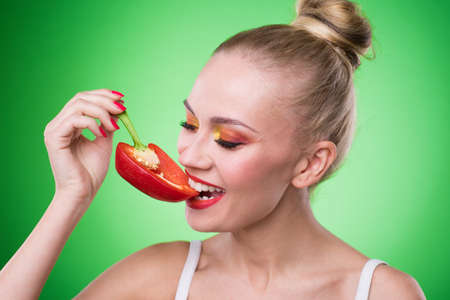 Young sports sexy girl in the studio on a green background with fresh vegetablesの写真素材