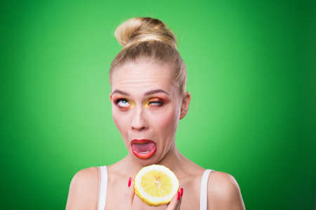 Young sports sexy girl in the studio on a green background with fresh fruitの写真素材