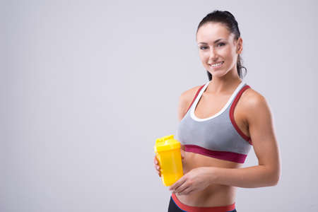 Young sportslooking nice lady with dark hair on the grey background in studioの写真素材