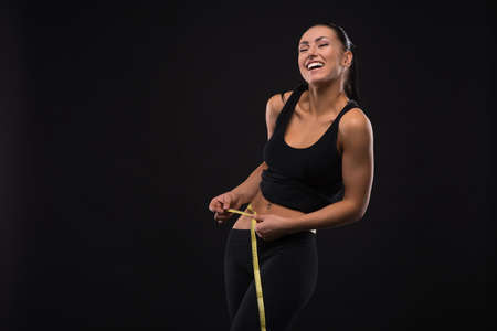 Young sportslooking nice lady with dark hair shows various performs exercises with equipment on the black background in studioの写真素材