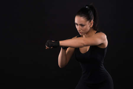 Young sportslooking nice lady with dark hair shows various performs exercises with equipment on the black background in studioの写真素材
