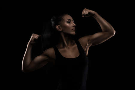 Young sportslooking nice lady with dark hair shows various performs exercises with equipment on the black background in studioの写真素材