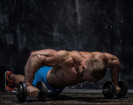 Handsome muscular man bodybuilder posing in the studio on a darck backgroundの写真素材