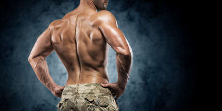 Muscular young man in studio on dark background shows the different movements and body partsの写真素材