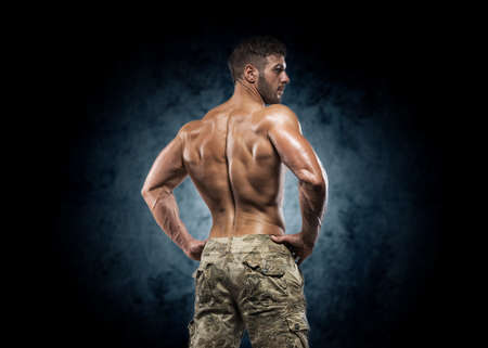 Muscular young man in studio on dark background shows the different movements and body partsの写真素材