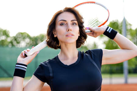 Beautiful young girl on an open tennis court playing tennisの写真素材