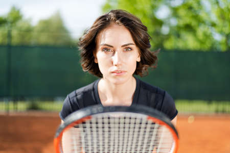 Beautiful young girl on an open tennis court playing tennisの写真素材