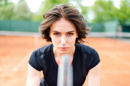 Beautiful young girl on an open tennis court playing tennisの写真素材