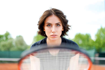 Beautiful young girl on an open tennis court playing tennisの写真素材