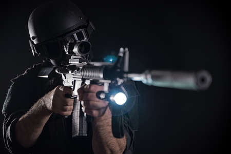 Spec ops police officer SWAT in black uniform on a studio backgroundの写真素材