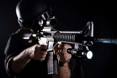 Spec ops police officer SWAT in black uniform on a studio backgroundの写真素材
