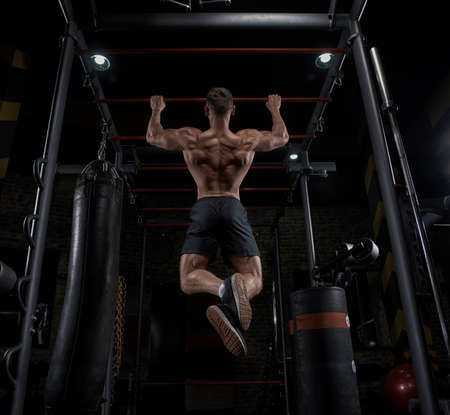 Muscular man working out in gym doing exercises, strong male naked torso abs.