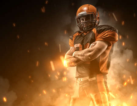 American football player on dark background in smoke and sparks in black and orange outfit.の写真素材