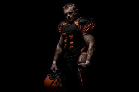 American football player on a dark background in black and orange equipment.の写真素材