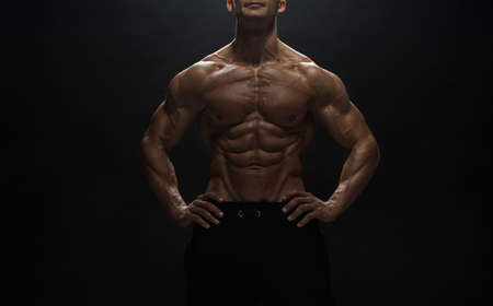 Fitness model Man posing in the studio. Dark background.の写真素材