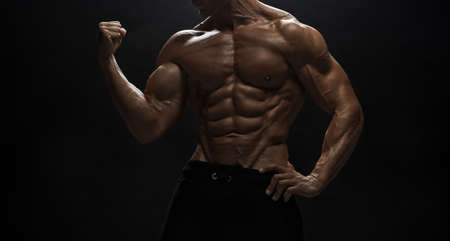 Fitness model Man posing in the studio. Dark background.