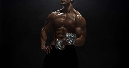 Fitness model Man posing in the studio. Dark background.