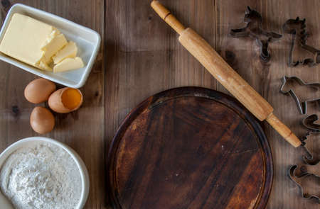 Wooden rustic table with everything you need for baking cookies: rolling pin, eggs, flour, molds to cut biscuitsの写真素材