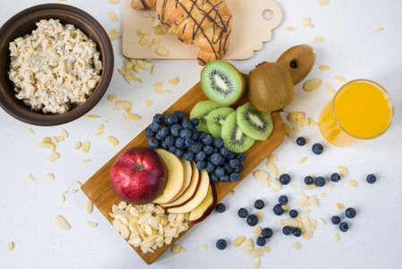 Oatmeal with kiwi, apples, almonds and blueberries. Amended orange juice in a glass, croissant and...