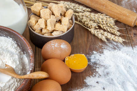 Selection of all necessary products for the preparation of dough - milk, butter, eggs, sugar, flour. On wooden table, top view, copy spaceの写真素材
