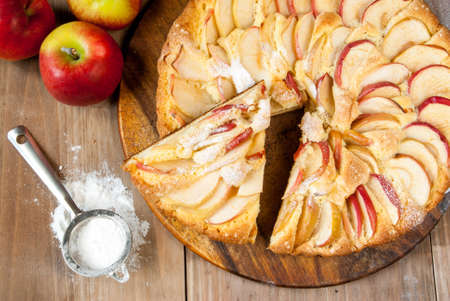 Traditional apple pie on a wooden table, with apple, powdered sugarの写真素材