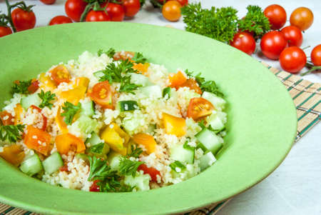 Couscous salad with fresh vegetables, close - tomato and greens, close viewの写真素材
