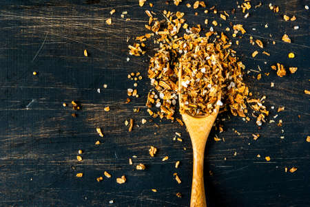 Seasoning. A mixture of salt and spices for cooking, with a wooden spoon for spices on a black wooden table. top view, copy spaceの写真素材