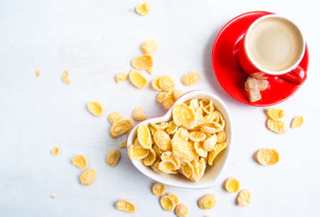 Light romantic breakfast: delicious coffee and corn flakes in bowl in the form of heart. Top view, copy spaceの写真素材