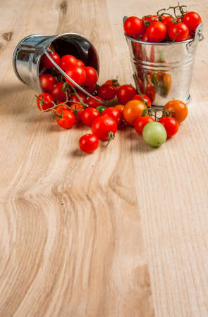 Tiny baby tomatoes in a small bucket on a wooden table. Copy spaceの写真素材