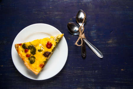 Slice of freshly baked homemade pie quiche lorraine on a dark blue wooden table, top view, copy spaceの写真素材