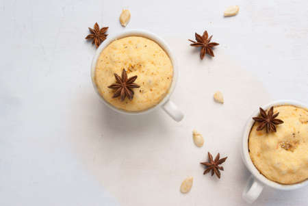 Pumpkin mug-cakes on a white wooden table, surrounded by spices and pumpkin seeds, top view, copy spaceの写真素材