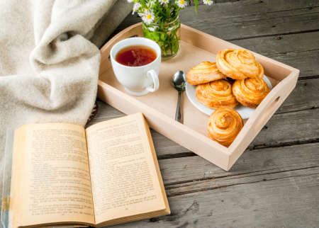 Cozy breakfast in spring or early autumn tea, freshly baked scones and bouquet of field's daisy and fascinating book. Copy spaceの写真素材