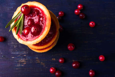 Winter one bite-sized snack or dessert: tartlets with sweet and sour cranberry sauce, decorated with rosemary.の写真素材