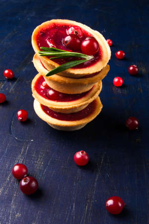 Winter one bite-sized snack or dessert: tartlets with sweet and sour cranberry sauce, decorated with...