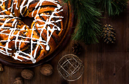 Christmas cakes: sweet fragrant ring with a poppy and sugar glaze close to the pine branches and Christmas decorations, copy spaceの写真素材