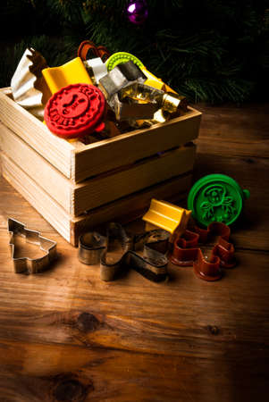 Cookie cutters for making Christmas cookies and stamps in a wooden box and scattered on the wooden...