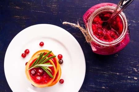 Winter one bite-sized snack or dessert: tartlets with sweet and sour cranberry sauce, decorated with rosemary. Top viewの写真素材