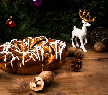 Christmas cakes: sweet fragrant ring with a poppy and sugar glaze close to the pine branches and Christmas decorations, copy spaceの写真素材