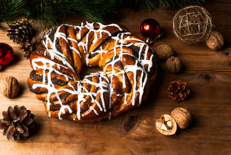 Christmas cakes: sweet fragrant ring with a poppy and sugar glaze close to the pine branches and Christmas decorations, copy space.の写真素材