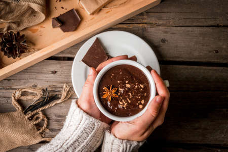 Girl drinks hot chocolate mug, with christmas present on rustic table with blanket or plaid from above, cozy and tasty breakfast or snack. Hands in picture, top viewの写真素材
