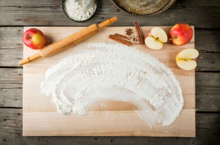 Cooking apple pie, kitchen table, flour, apples, pastry, tools for working with the dough. View from...