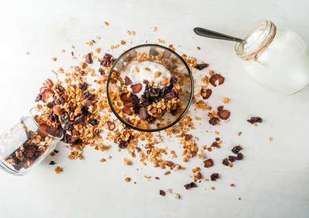 homemade granola with dried fruits and nuts, organic yogurt in jar. Rustic wooden table. Top view