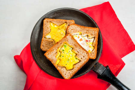 Funny food for kids, Christmas breakfast: toast with scrambled eggs in the shape of Christmas trees and stars, on with table top view, copy spaceの写真素材