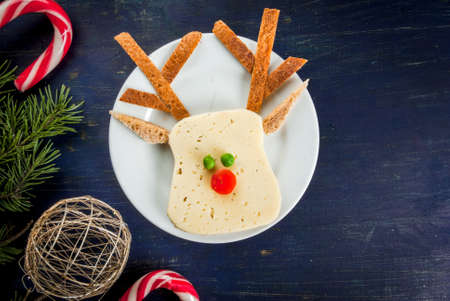 Funny Christmas breakfast, a sandwich for a child in the form of the muzzle of the deer (cheese, bread, vegetables), With branches of Christmas trees and decorations, top view, copy spaceの写真素材