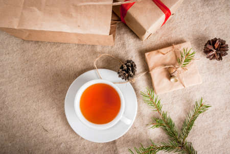 Gift wrapping and letters, cards for Christmas greetings. Envelopes with letters, gifts, Christmas tree branches and pine cones are on a wooden table lie, a cup of fragrant hot tea, top viewの写真素材