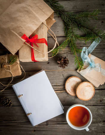 Gift wrapping and letters, cards for Christmas greetings and notepad. Envelopes with letters, gifts, Christmas tree branches and cones, a cup of fragrant hot tea, top view, copy spaceの写真素材