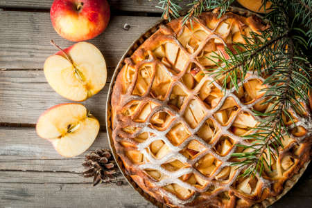 Traditional american apple pie on rustic wooden table, with apple. Near the Christmas tree branches and pine cones, top viewの写真素材