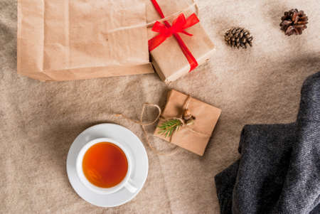 Gift wrapping and letters, cards for Christmas greetings. Envelopes with letters, gifts, Christmas tree branches and pine cones are on a wooden table lie, a cup of fragrant hot tea, top viewの写真素材