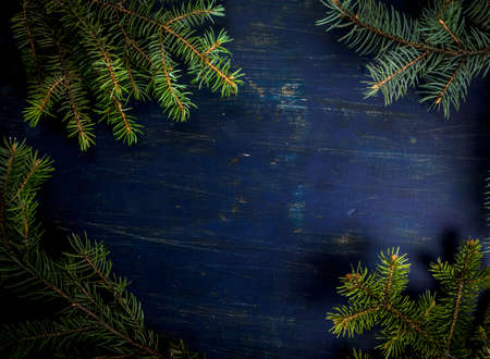 Christmas background dark blue wooden table with fir-tree branches, copy spaceの写真素材