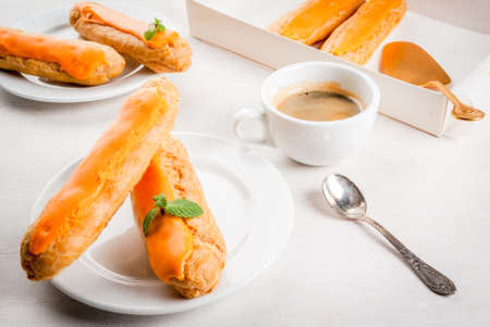 Eclairs with mango cream and  topping on a white wooden table. Drink tea or snack